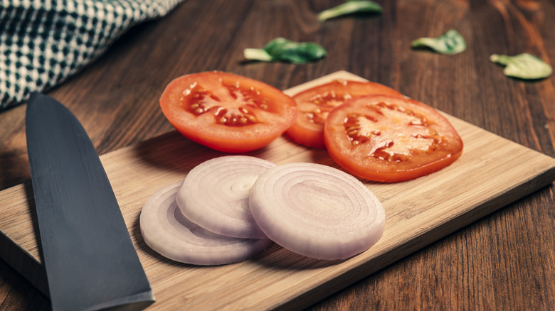 Tomato and onion slices on a cutting board