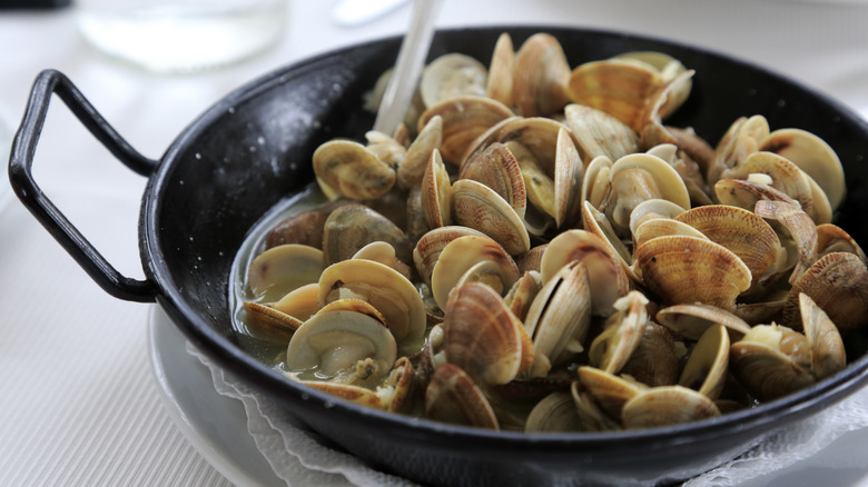 Cooked clams in a large pan with liquid