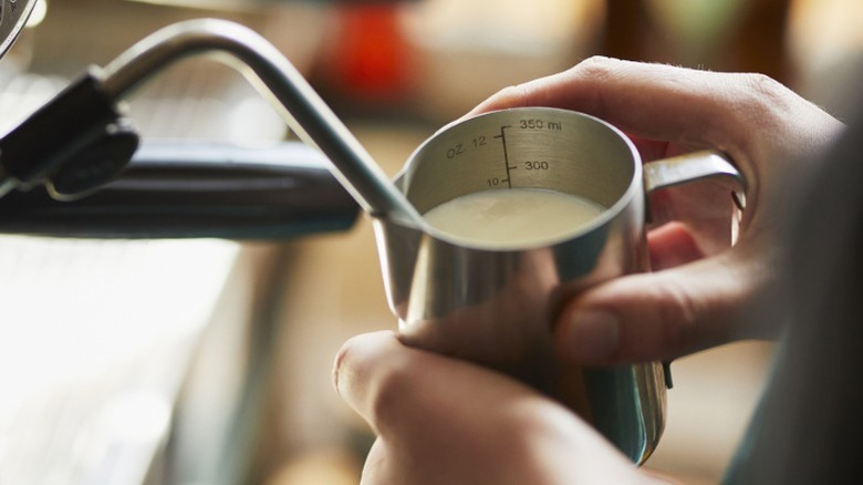 A person steaming milk for coffee using an espresso machine