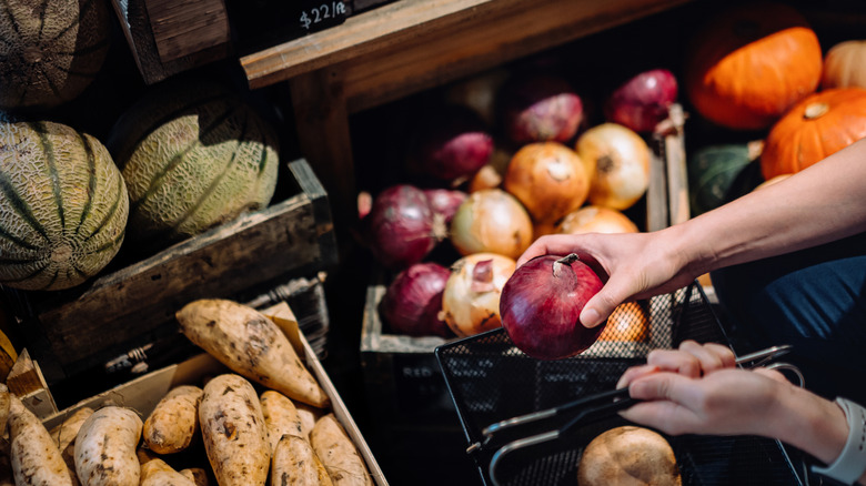 Person picking out fresh produce from wooden crates