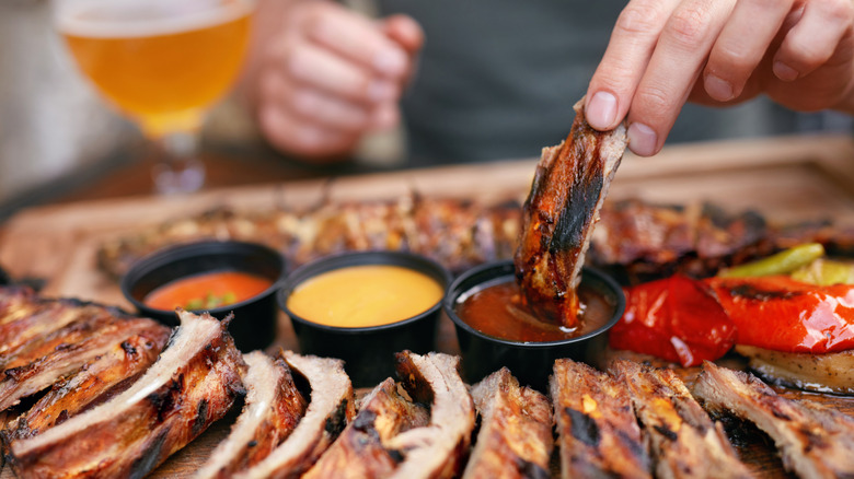 Hand dipping ribs in sauce