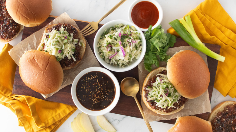 An overhead shot of several pork burgers topped with slaw