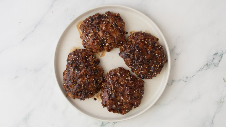 Grilled and glazed patties on a white plate
