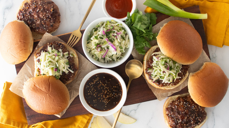 An overhead shot of several pork burgers topped with slaw