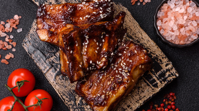 baby back ribs on a plank with salt and tomatoes nearby