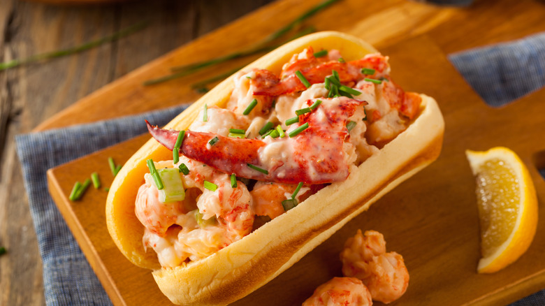 A flatlay of a creamy lobster roll placed atop a wooden cutting board.