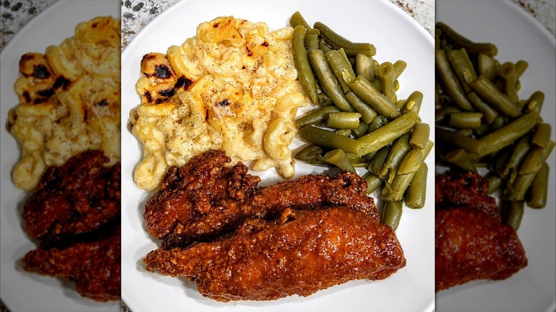 Sauce-covered chicken tenders, macaroni and cheese, and green beans on a white plate