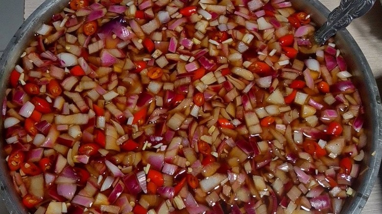 A big pot filled with Filipino spiced vinegar, where onions and chili are floating