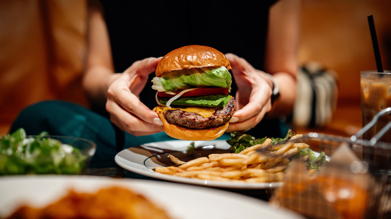 Person holding a burger in a restaurant.