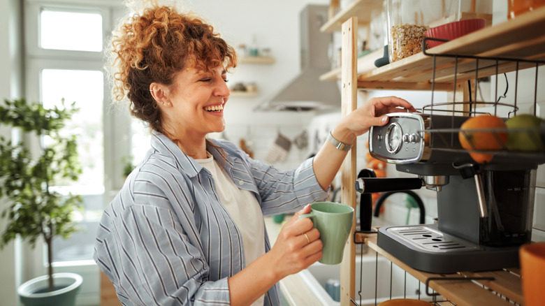 Person using a coffee maker on a kitchen shelf