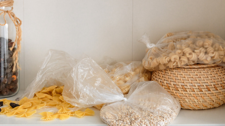 pantry shelf littered with bags of pasta and seeds