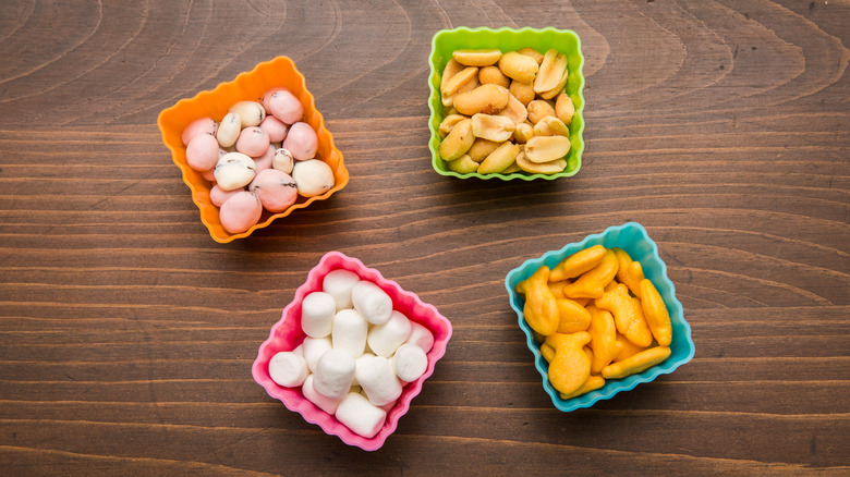 small square snack containers with crackers, nuts, and marshmallows