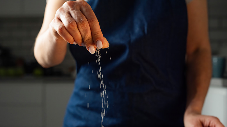 Woman sprinkling food with salt