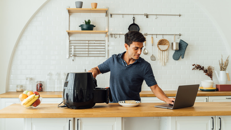 man looks at recipe while cooking with air fryer