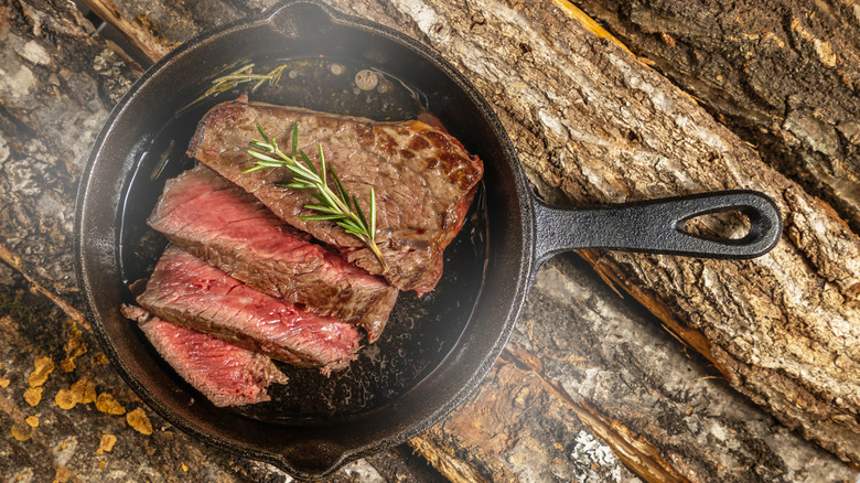 Steak cooked in a cast iron, sliced and topped with a rosemary branch