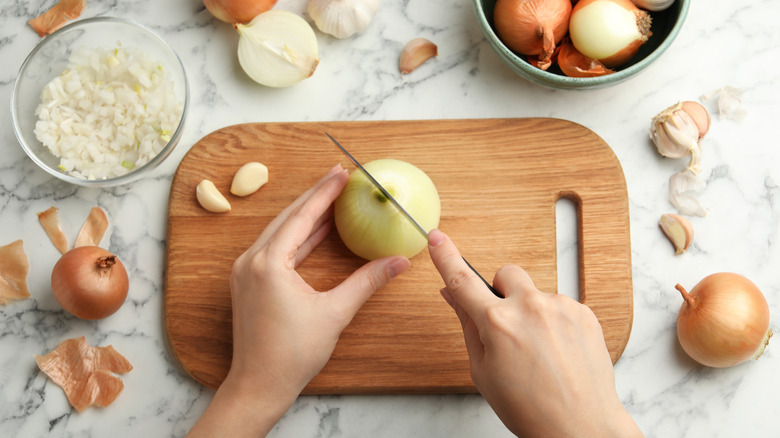 A person in the middle of cutting onions