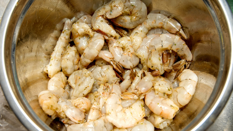 Marinated raw shrimp in a metal bowl.