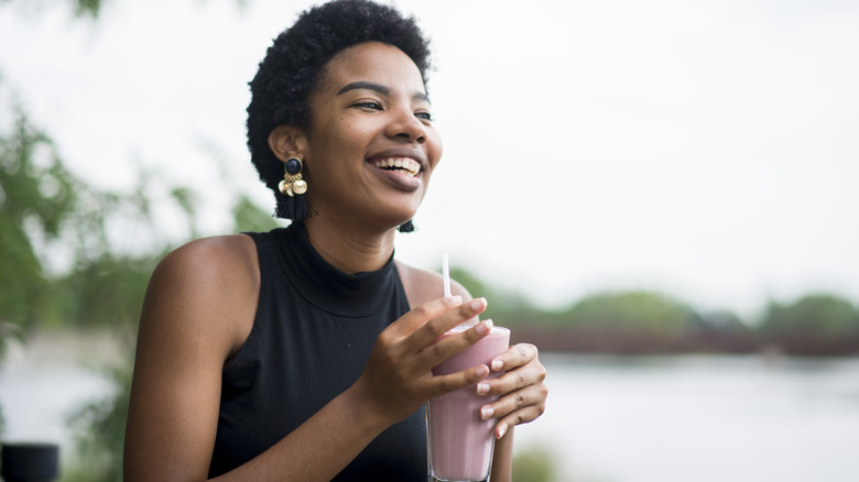 Smiling woman with a pink drink in a glass with a straw
