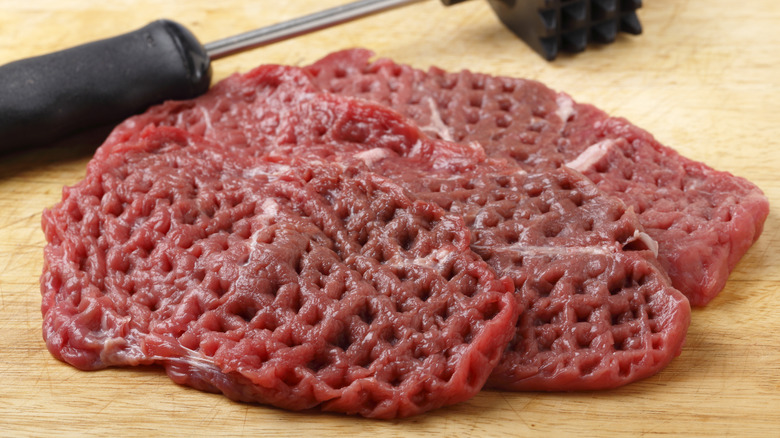 Three cube steaks with square indentations, stack on each other.