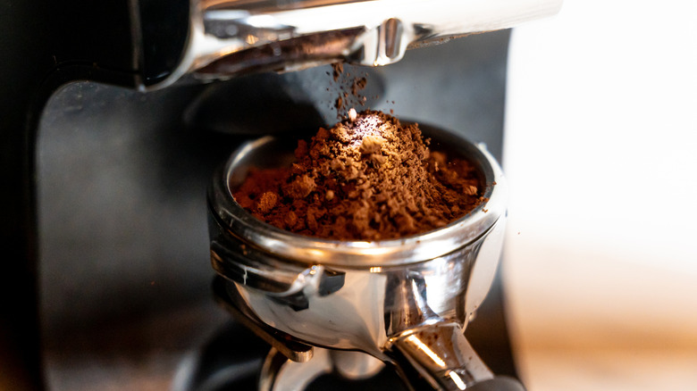 Coffee grounds coming out of an espresso machine.
