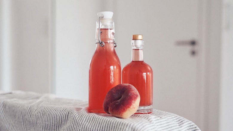 glass bottles with syrup and a peach on the side