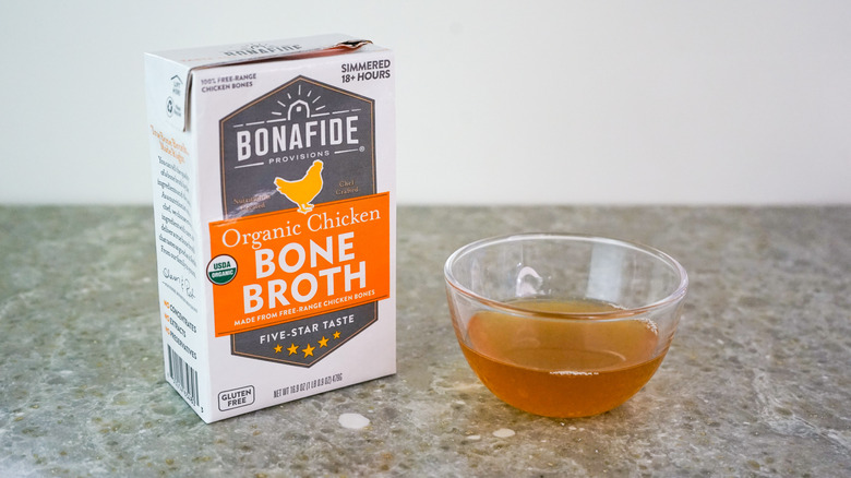 Carton of Bonafide Provisions Organic Chicken Bone Broth next to glass bowl of broth