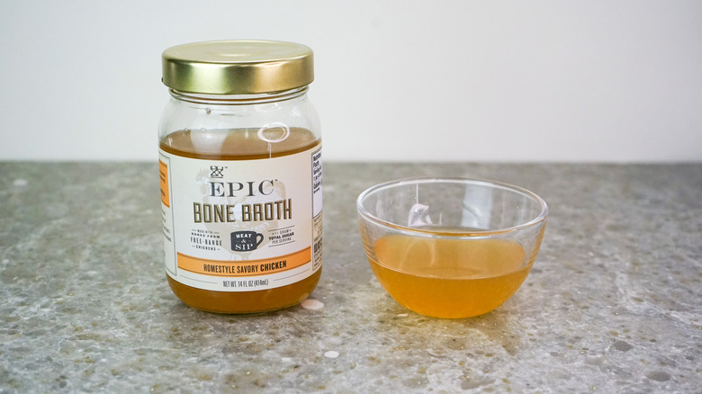 Jar of Epic homestyle Savory Chicken Bone Broth next to glass bowl of broth