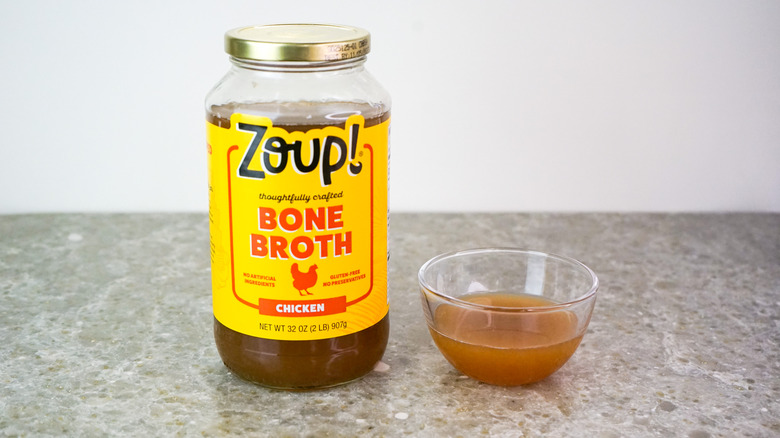 Jar of Zoup! Fresh Soup Company Chicken Bone Broth next to glass bowl of broth