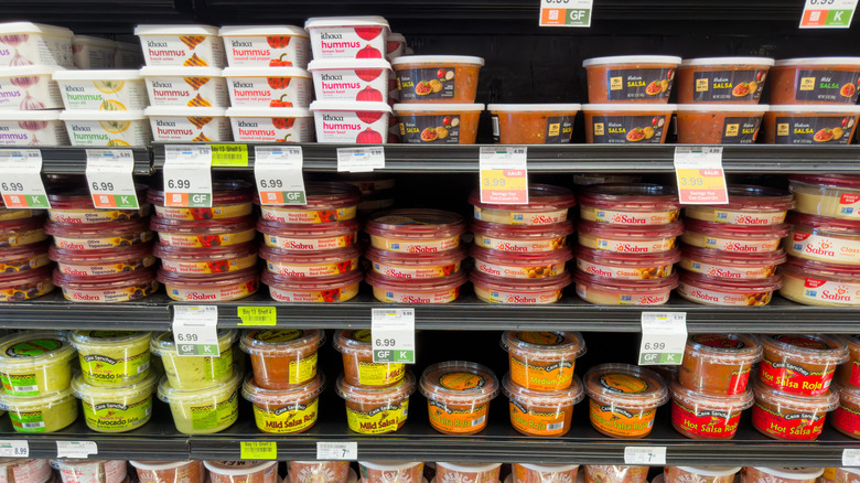 Several packaged dips line store shelves.