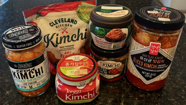 A group of store-bought kimchi containers on black table