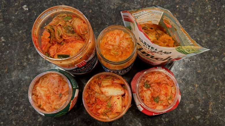Overhead view of open containers of kimchi on black table