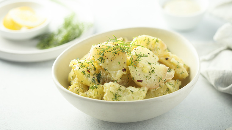Potato salad flavored with dill in a white bowl