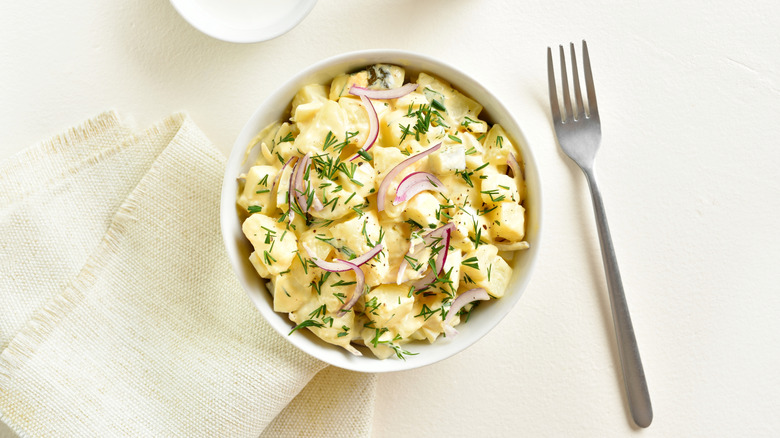 Potato salad with fresh ingredients on white table