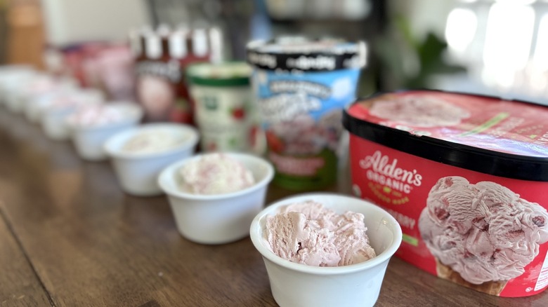 lineup of strawberry ice cream brands in tubs and bowls