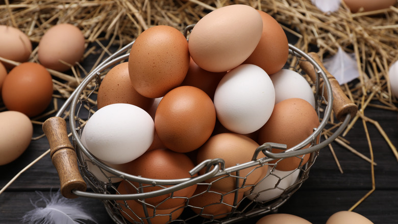 a basket of farm fresh eggs near hay and feathers