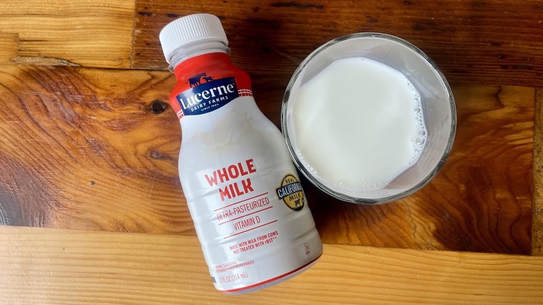Overhead view of glass and bottle of Lucerne Whole Milk lying on a wooden table top