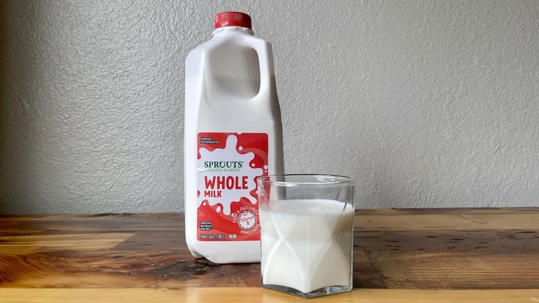 Carton and glass of Sprouts Whole Milk on a wooden table