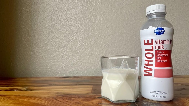 Glass and bottle of Kroger Whole Milk on a wooden table