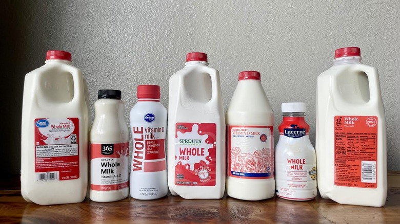 Lineup of various store-brand milks on a wooden table