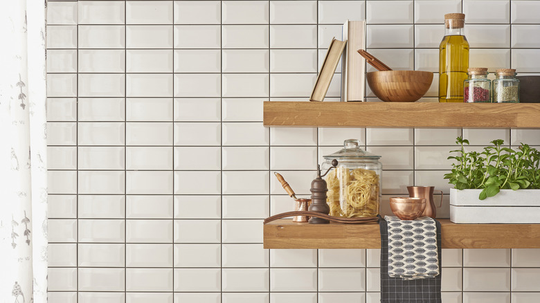 floating shelves in a kitchen holding olive oil, pasta, spices, books, and herbs
