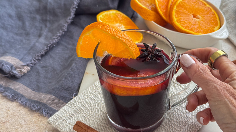 hand holding mug of mulled wine with garnishes