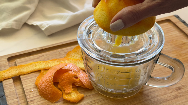 hand juicing orange over juicer