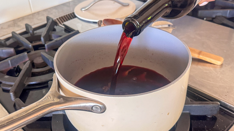 Red wine pouring from bottle into saucepan