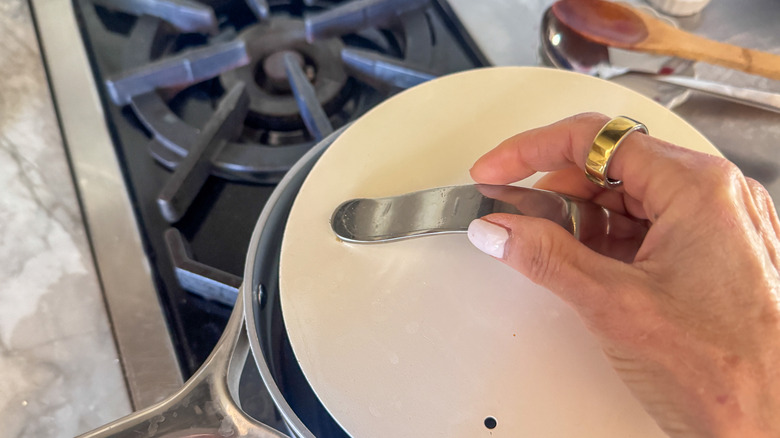 Hand covering saucepan with lid