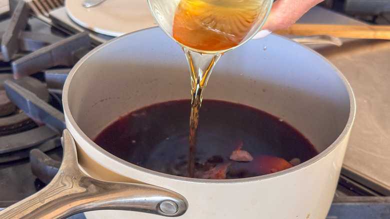 pouring brandy into pot with mulled wine