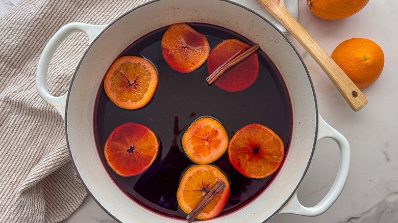 pot of mulled wine with orange slices and cinnamon sticks