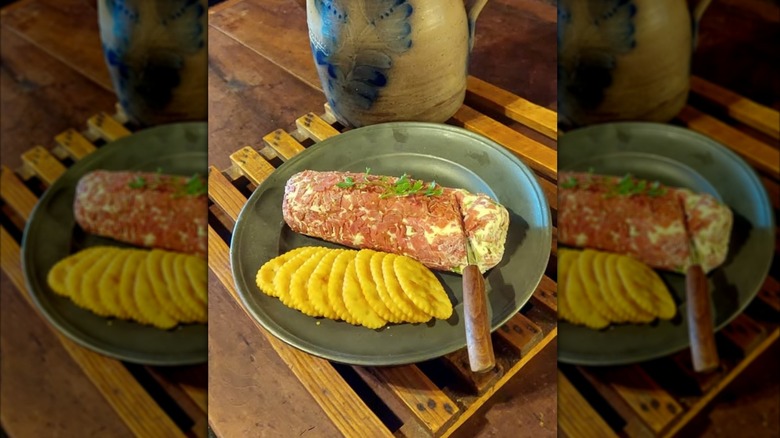 A Dried Beef Log on a plate with some crackers and a knife