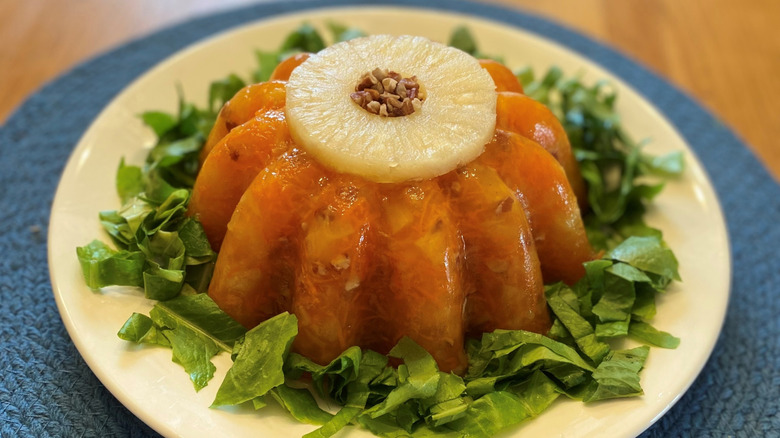 A vintage Jell-O salad sits on a plate and is garnished by a pinneapple ring