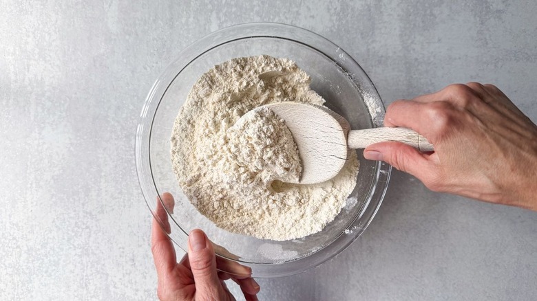 Mixing biscuit dry ingredients in glass bowl with wooden spoon