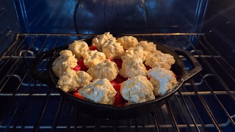 Strawberry and cardamom biscuit cobbler baking in cast iron skillet in oven